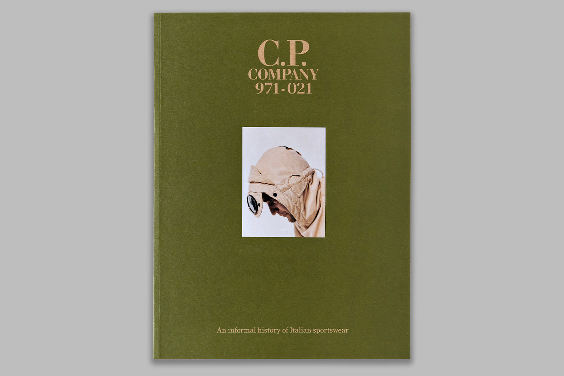 Green cover of C.P. Company 971–021, featuring a photograph of a hooded goggle jacket.